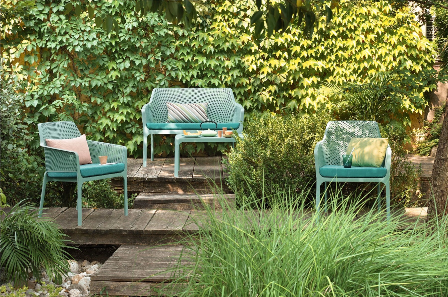 Turquoise Nardi seating in a leafy garden